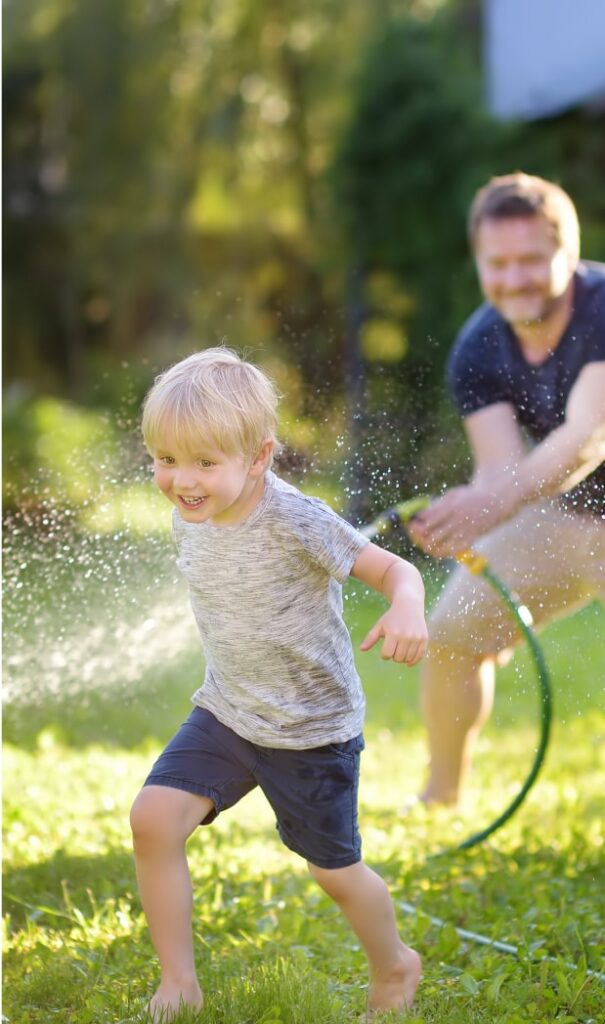 boy being sprayed by a hose by his father